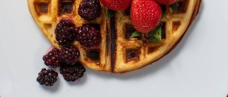 A waffle topped with strawberries and berries on a white plate.