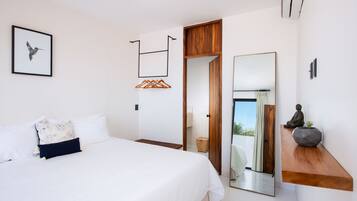 Un dormitorio moderno con una cama grande, un estante de madera, un espejo y una lámpara colgante.