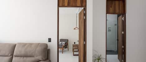 A modern living room with a sofa, wooden doors, a hanging plant, and a bench.