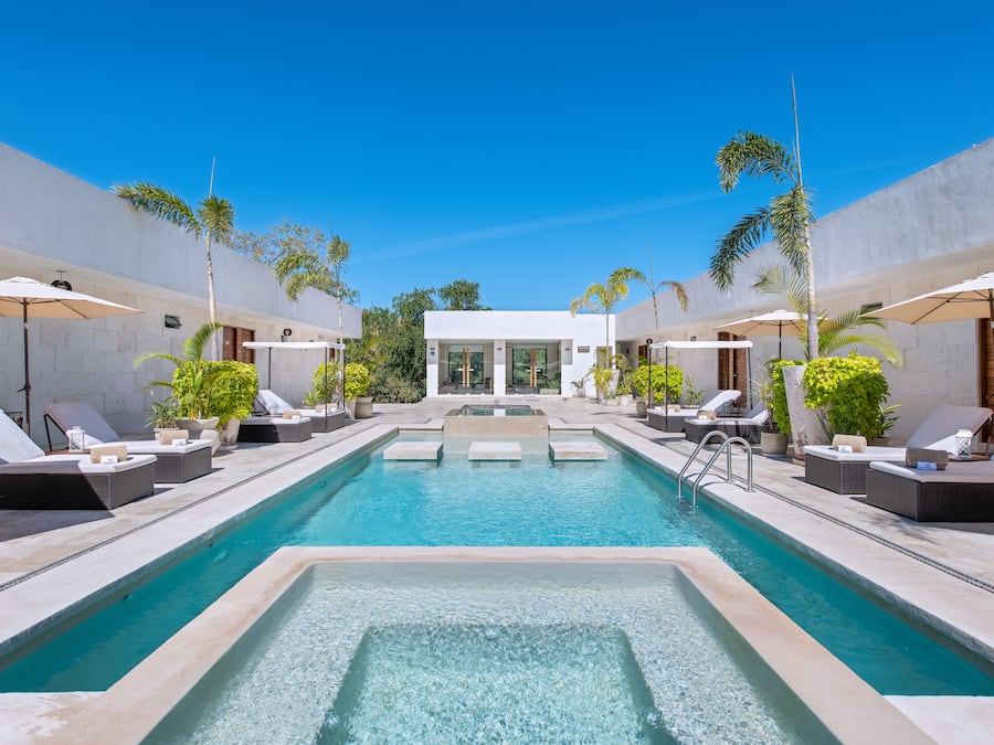 Una piscina al aire libre, sombrillas, sillones reclinables de piscina