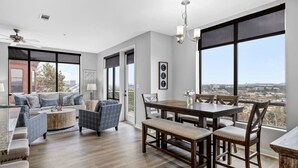 Un vaste salon comprenant un coin repas, de grandes fenêtres et une vue sur la ville.