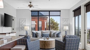Un salon moderne comprenant un canapé, deux fauteuils, une table basse et un téléviseur.