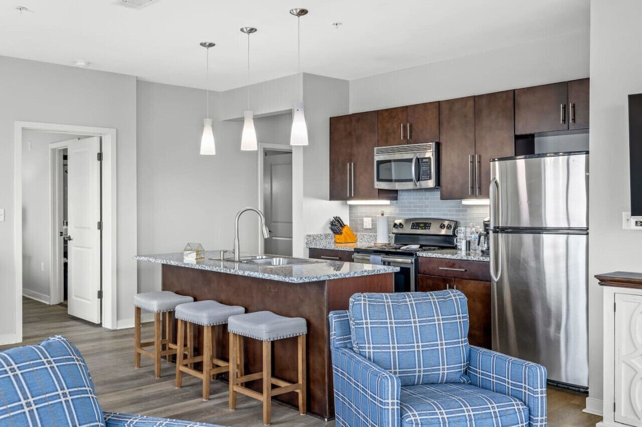 Una cocina moderna con armarios de madera oscura, electrodomésticos de acero inoxidable y una isla central con taburetes de bar.