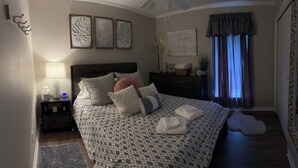 Een keurig opgemaakt slaapkamer met een groot bed, nachtkastjes, een dressoir en een spiegel.