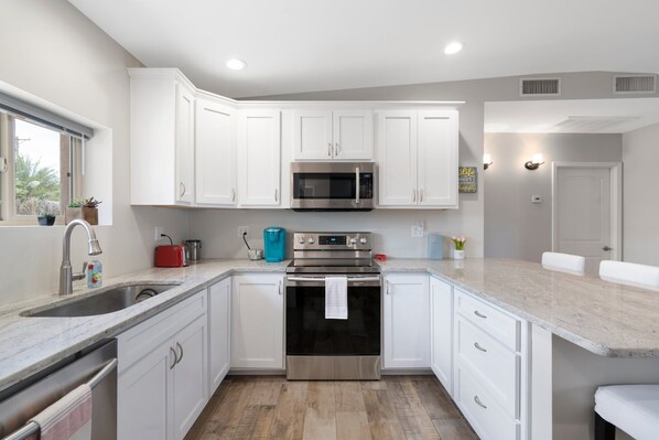 Equipped with a microwave, oven, and granite countertop, this kitchen offers ample space for meal preparation.