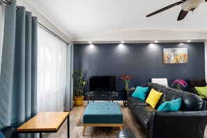Relax in this stylish living room with a black leather sofa, flat-screen TV, and wooden coffee table.