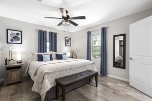Cozy retreat with a large bed, bench, and ceiling fan.