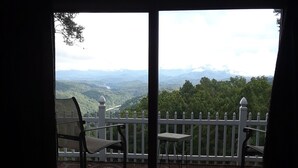 Ein Zimmer mit Blick auf eine gebirgige Landschaft durch eine Glastür.