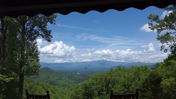 Eine Holzterrasse mit zwei Stühlen mit Blick auf eine gebirgige Landschaft.