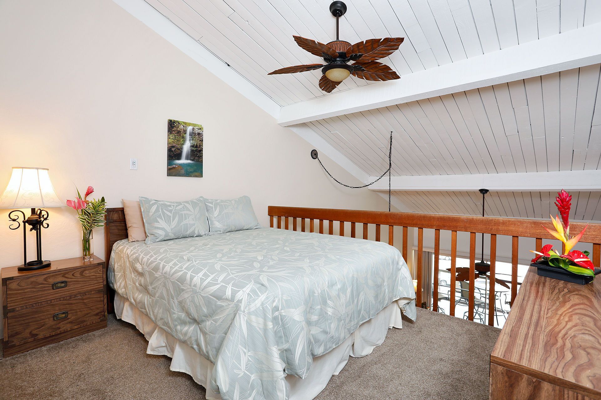 A bedroom with a bed, nightstand, lamp, and a ceiling fan.