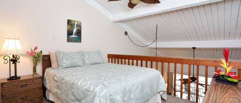 A bedroom with a bed, nightstand, lamp, and a ceiling fan.