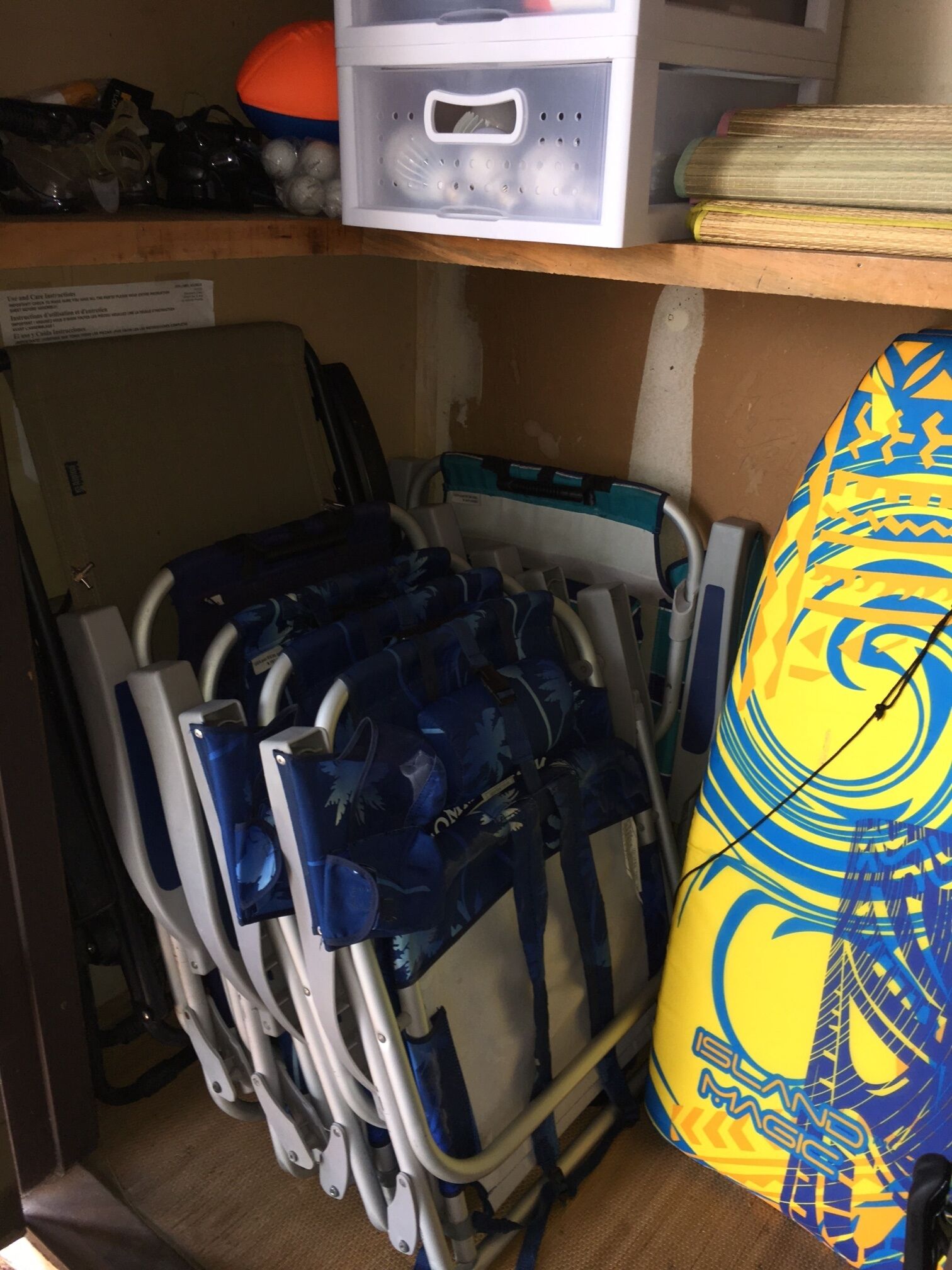 A storage area with a wheelchair, a blue and yellow bag, and a shelf with various items.