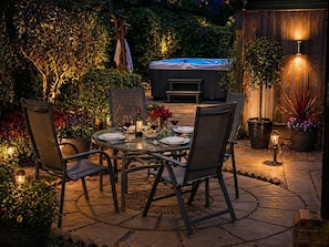 An outdoor patio with a table set for dining, surrounded by chairs and potted plants.