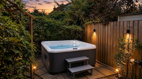 Un bain à remous dans un jardin, avec une clôture en bois et des marches menant à celui-ci.. Measure Cottage - Sleeps up to 4 - Henley in Arden - HOT TUB