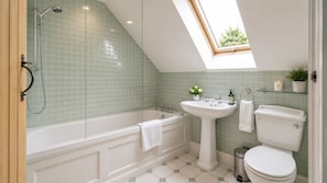 A bathroom with a skylight, a bathtub, a sink, and a toilet.