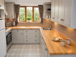 A kitchen with a central island, a window with curtains, a sink, and a stove.