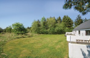 Guests can relax in a serene outdoor setting surrounded by trees and a tranquil lawn.