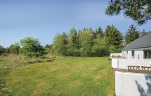 Guests can relax in a serene outdoor setting surrounded by trees and a tranquil lawn.