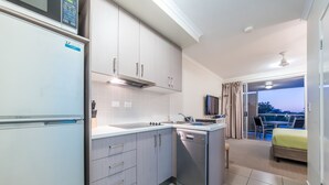 Una cocina moderna equipada con lavavajillas, microondas y un lavabo. Hay un balcón con vistas al cielo.