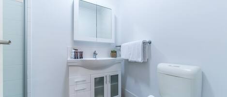 A modern bathroom with a white sink, mirror, and toilet.