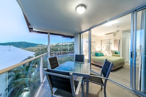 Enjoy unobstructed views of the lush hillside from the balcony, where a glass table and four chairs await.