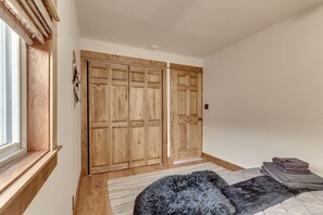 A bedroom with a large window, wooden wardrobe, and a fluffy rug. - Yellowstone Lodge    (Gardiner)