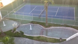 Ein Hallen-Tennisplatz mit drei Wasserspielen und Palmen.