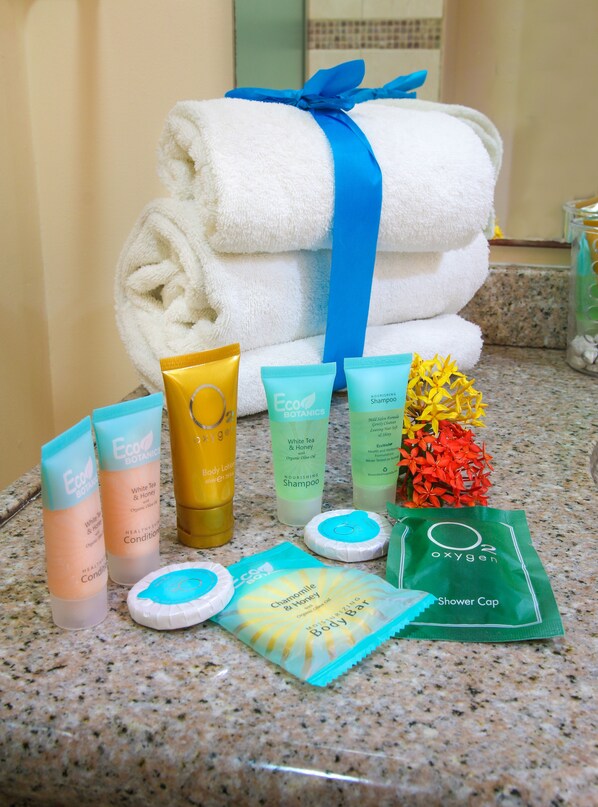 A bathroom counter with various toiletries including body lotion, shampoo, and a shower cap. - Aqua Viva Suites (Kralendijk)