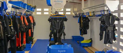 A diving shop with racks of diving gear, blue storage bins, and a sign indicating a local area.