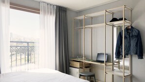 A bedroom with a bed, a desk with a laptop, a hanging shelf with clothes, and a view of the outdoors. - Bed Radio Dongmoon - Hostel (Jeju City)