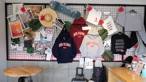 A wall display with various items including a hat, a skateboard, and several hoodies with "BED RADIO" branding. - Bed Radio Dongmoon - Hostel (Jeju City)
