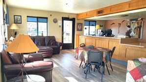 A cozy living room with a brown leather sofa, a round coffee table, and a dining area with a table covered by a colorful tablecloth. - Rodeway Inn Copper Stay Benson AZ I-10 Exit 304 (Benson)