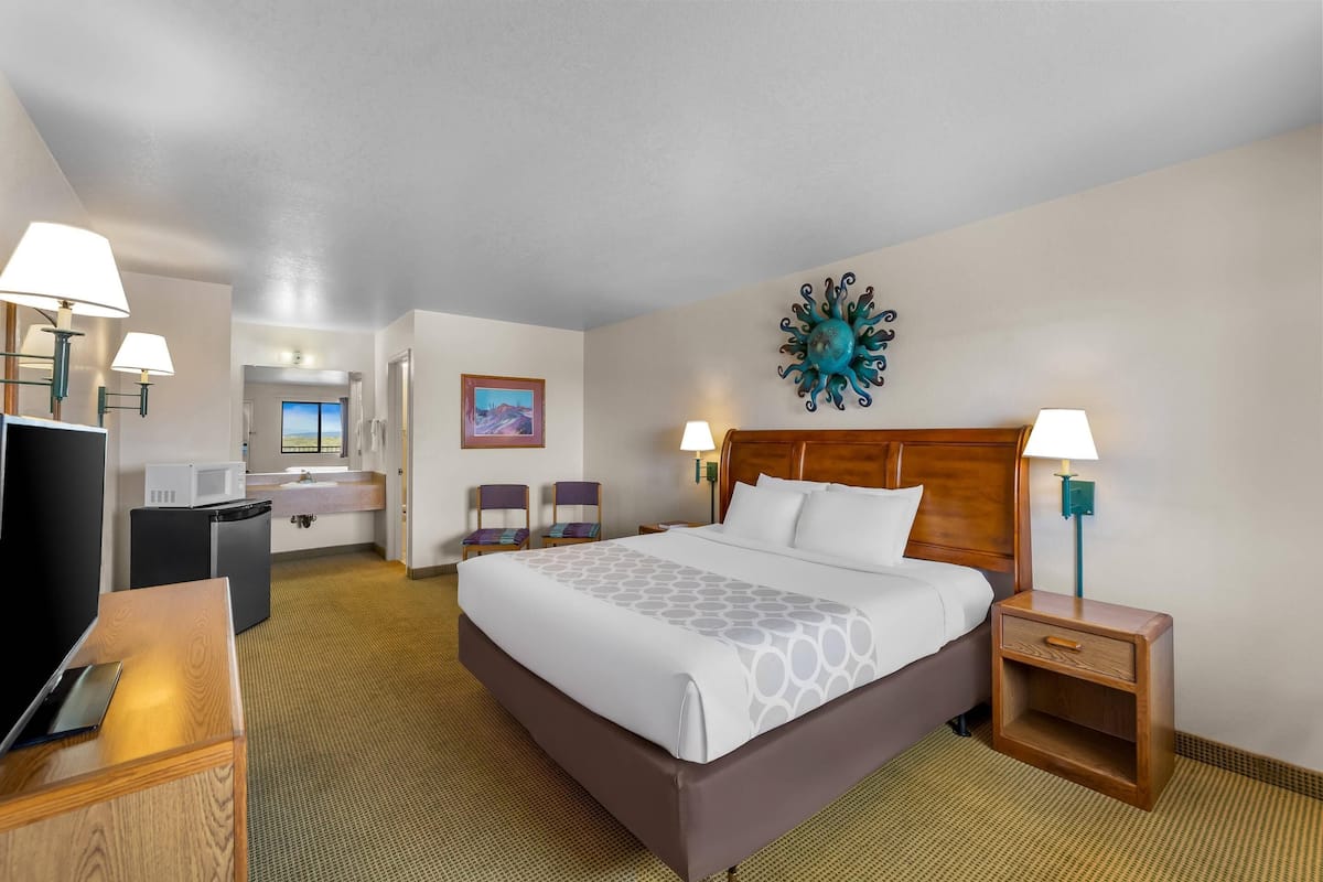 A hotel room with a large bed, bedside tables, a desk, and a view of the outside.