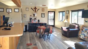 A well-lit room with a dining table, a leather sofa, a coffee station, and a kitchen area. - Rodeway Inn Copper Stay Benson AZ I-10 Exit 304 (Benson)