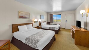A hotel room with two beds, a desk, a television, and a window with a view. - Rodeway Inn Copper Stay Benson AZ I-10 Exit 304 (Benson)
