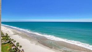 Una spiaggia con acque cristalline, una riva sabbiosa e alcune persone che passeggiano.