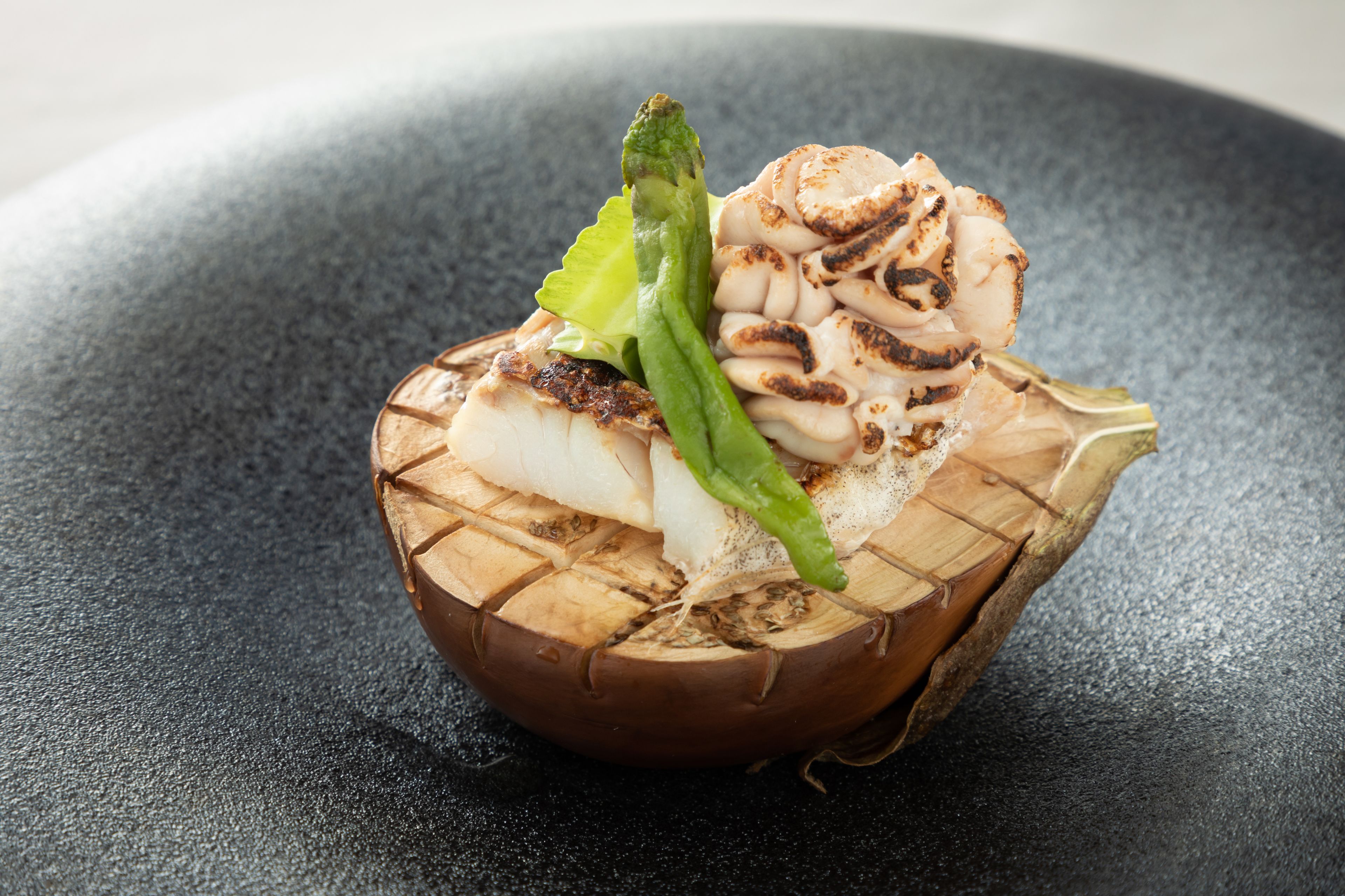 A dish with grilled chicken, asparagus, and mushrooms on a wooden bowl.
