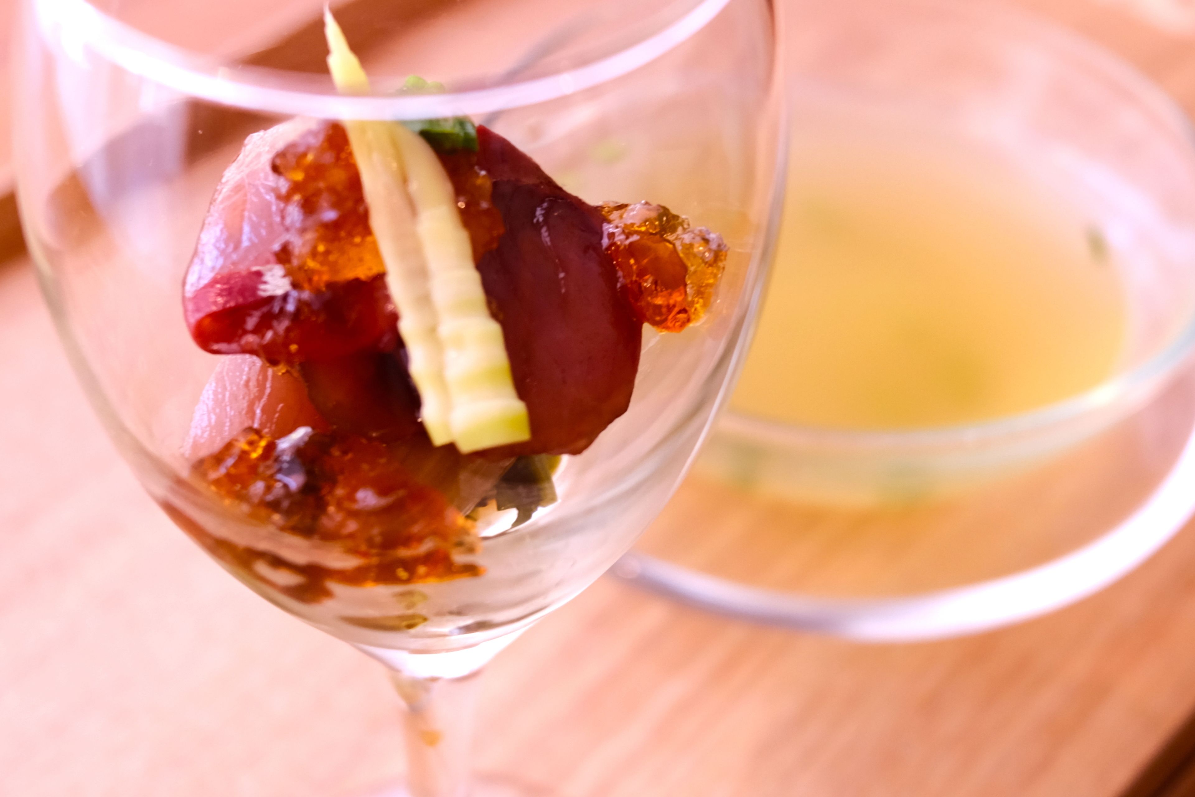 Un postre en un vaso, con un líquido transparente al fondo.