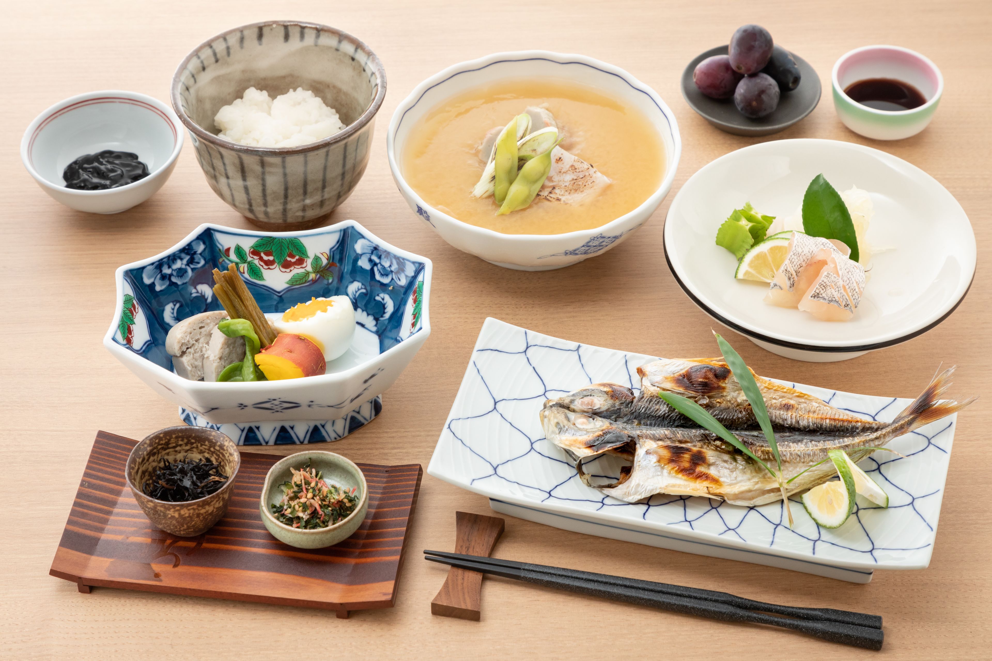 Ein Tisch mit verschiedenen Gerichten, darunter Reis, Suppe, Fisch und Gemüse.