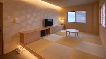 Una sala de estar moderna con suelo de tatami, un televisor de pantalla plana, una mesa consola de madera y una ventana con pantalla shoji tradicional.