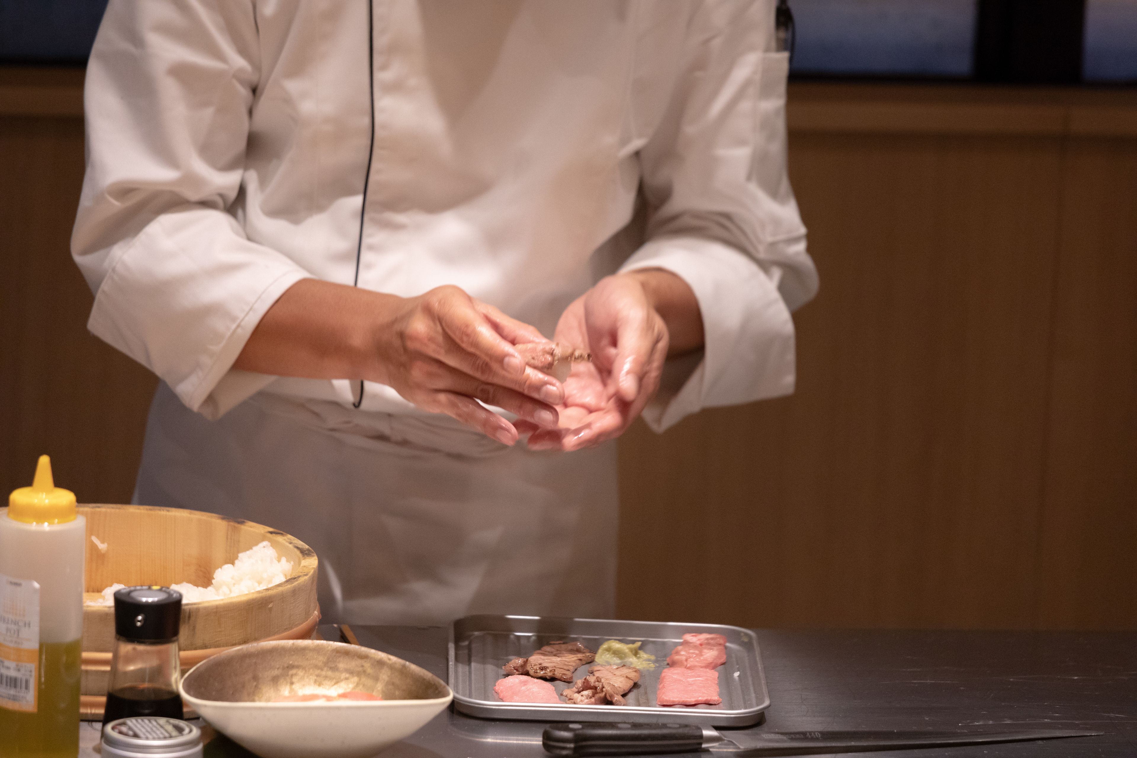 A chef preparing food with ingredients and utensils on a table.