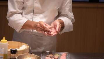 A chef preparing food with ingredients and utensils on a table.