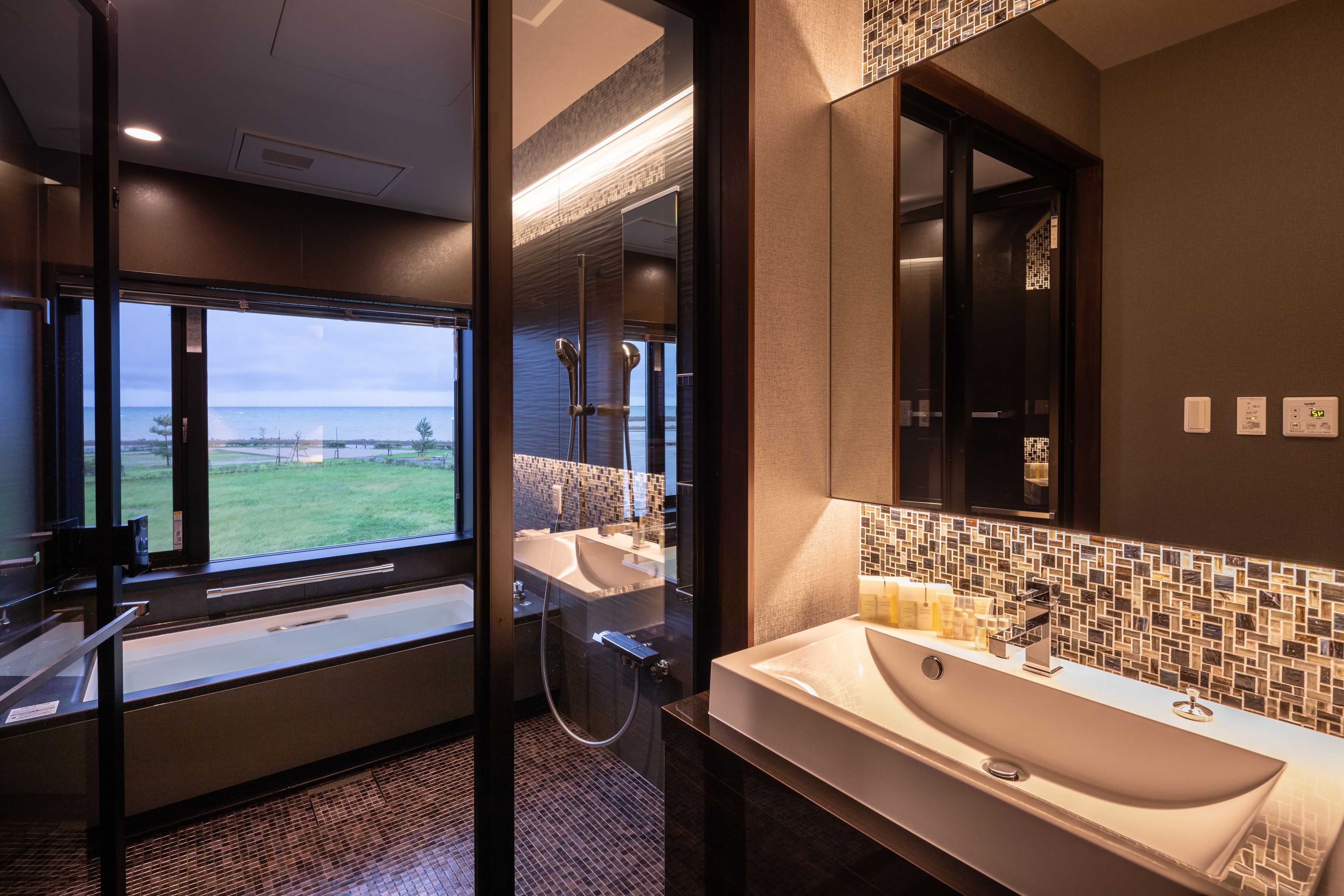 Une salle de bain moderne dotée d’une grande fenêtre, d’une baignoire, d’une douche et d’un lavabo.