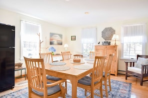 A dining room with a wooden table, chairs, and a refrigerator.