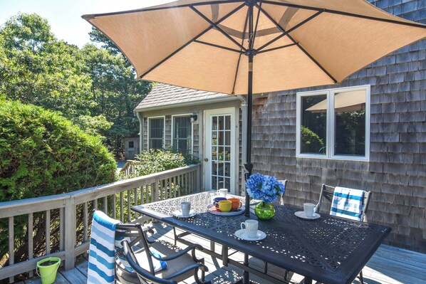 A patio with a table, chairs, and a large umbrella.