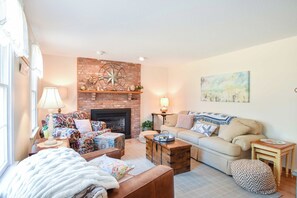 A cozy living room with a brick fireplace, a large painting, and a comfortable seating area.