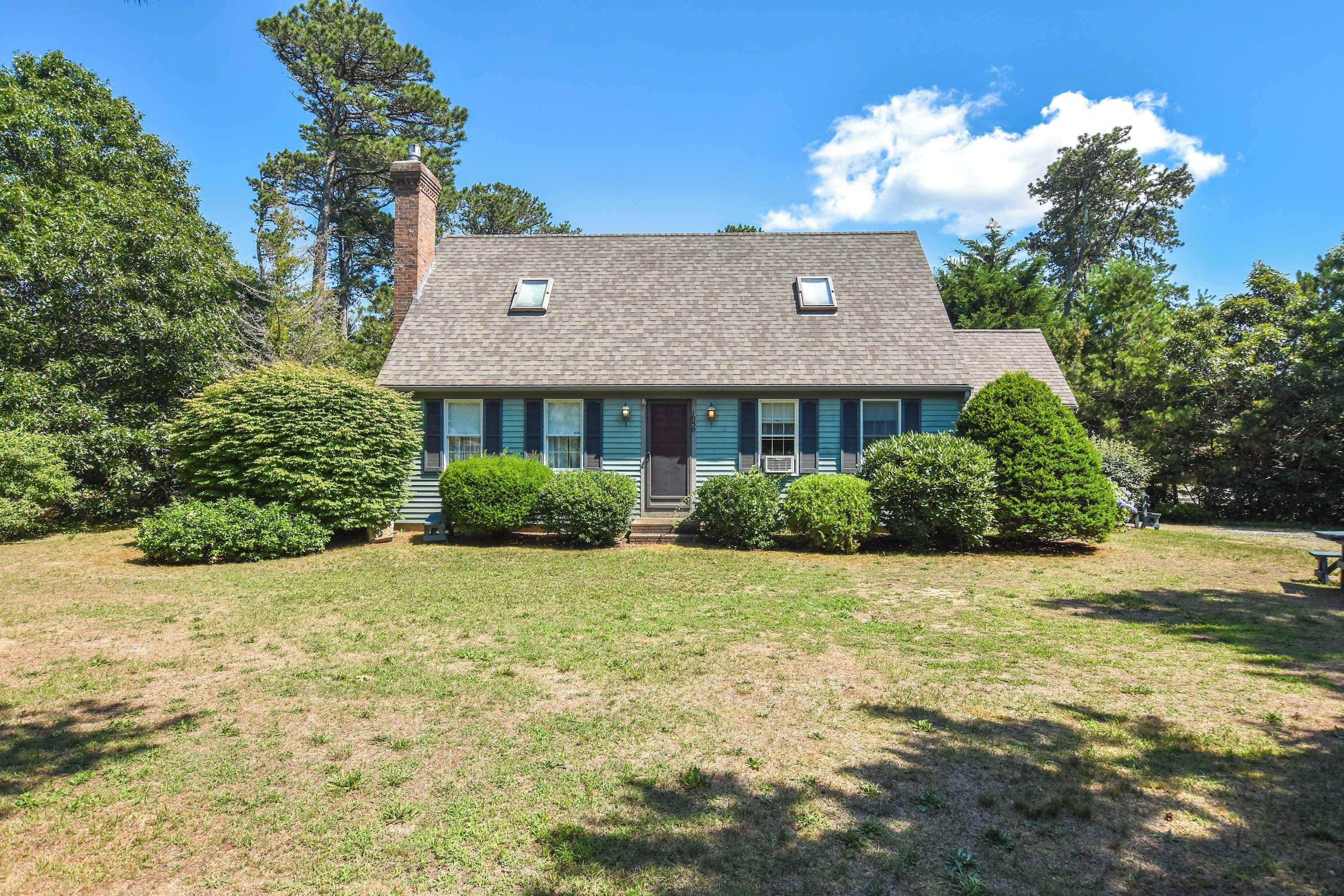A two-story house with a gabled roof, a chimney, and a front porch.