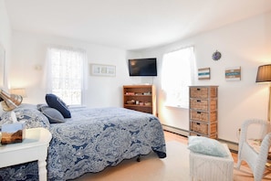 A bedroom with a bed, a TV, a bookshelf, a desk, and a chair.