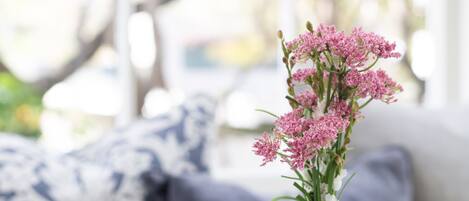 Un florero de vidrio transparente con flores rosadas sobre una mesa blanca.