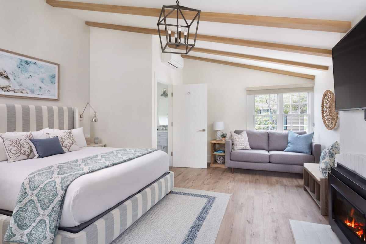 A bedroom with a bed, a sofa, a fireplace, and a window.